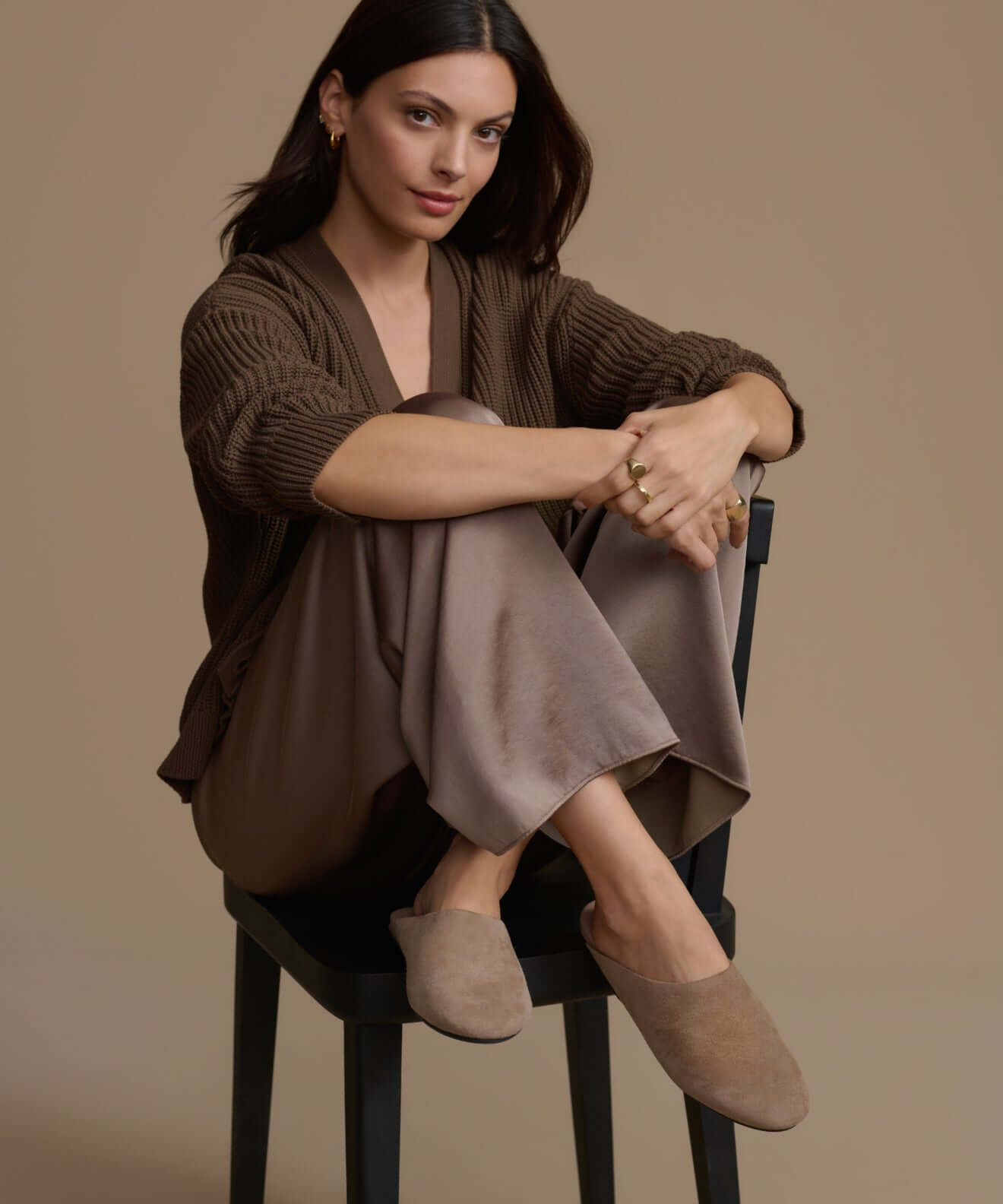 Woman sitting in a chair wearing stylish shoes and comfortable outfit, showcasing elegant shoes.