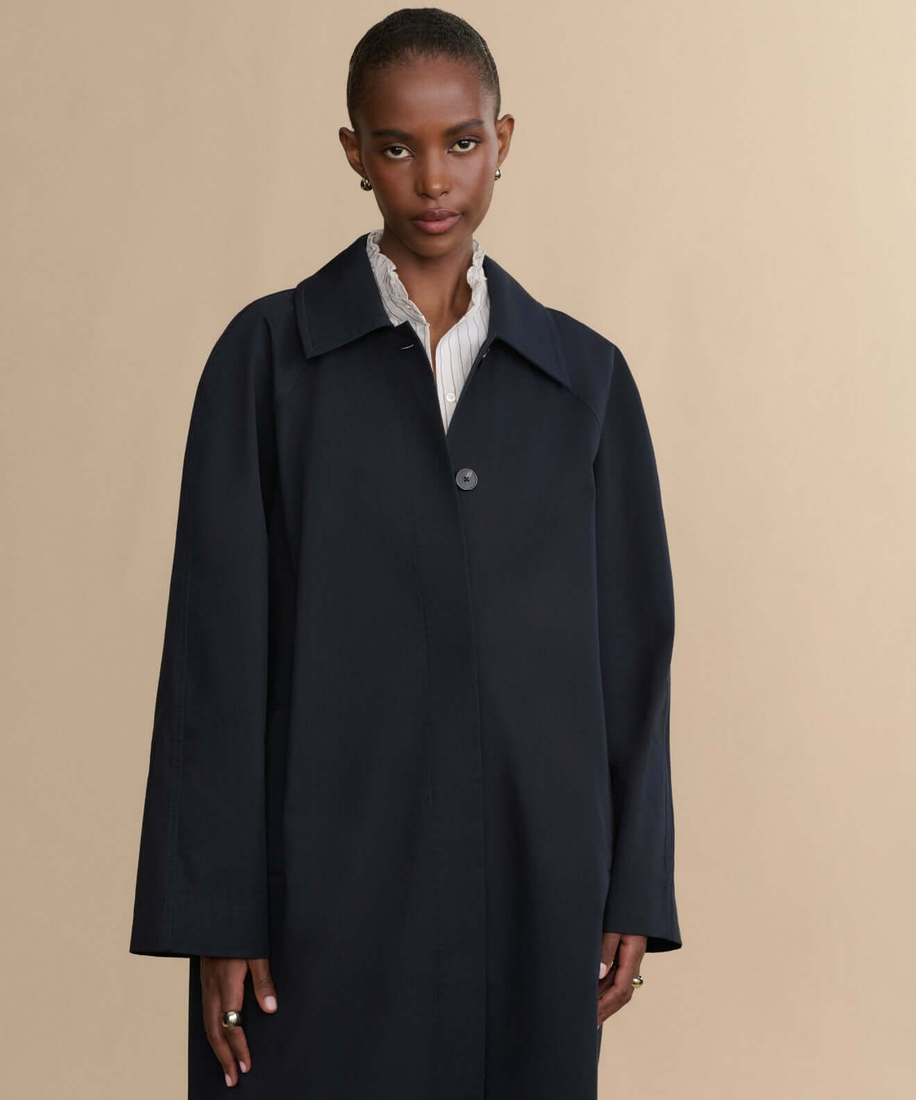 Model showcasing elegant dark outerwear coat against a neutral background, perfect for stylish layering in any season.