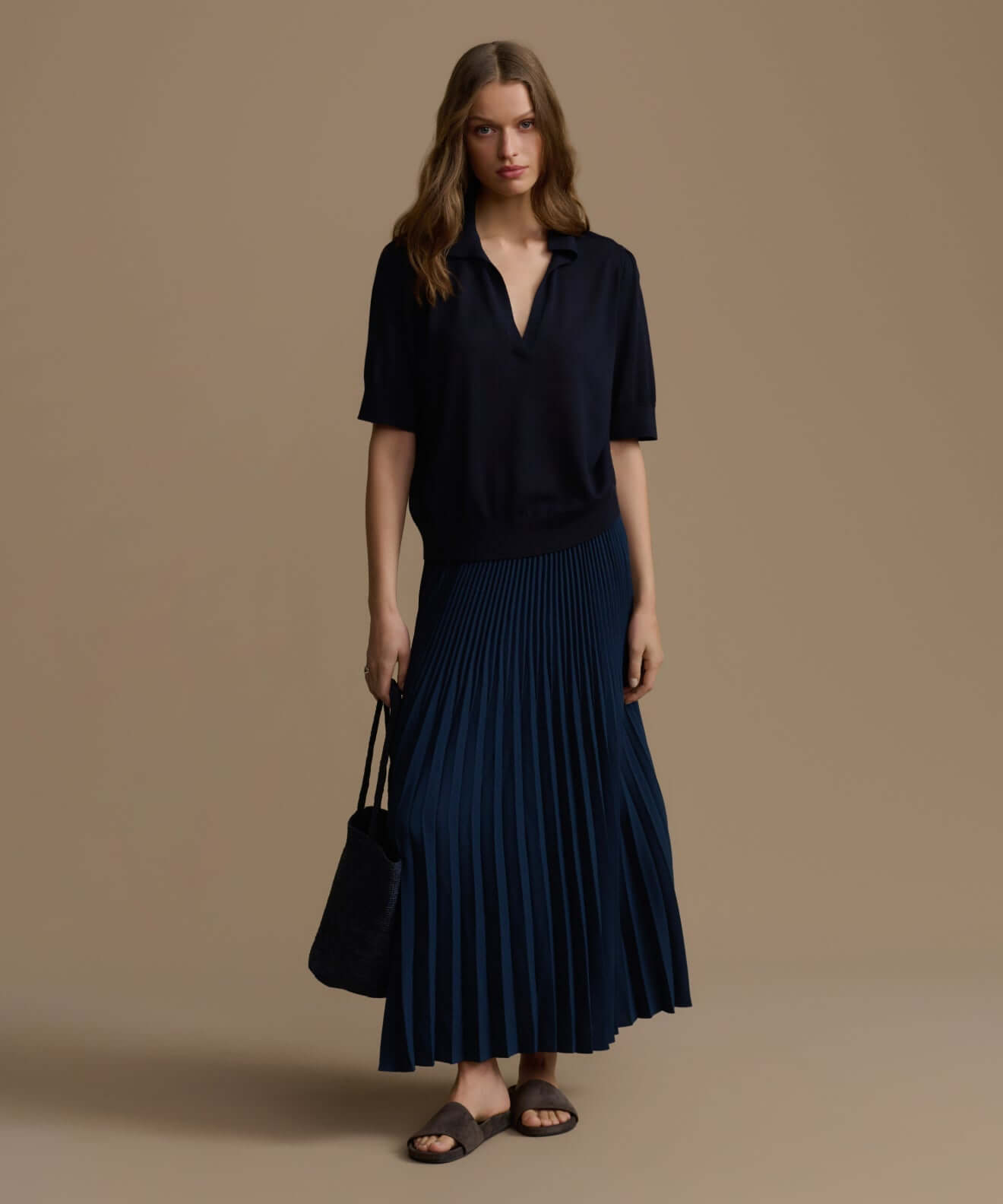 Model wearing a stylish outfit featuring pleated navy skirt and casual top, showcasing trendy bottoms.